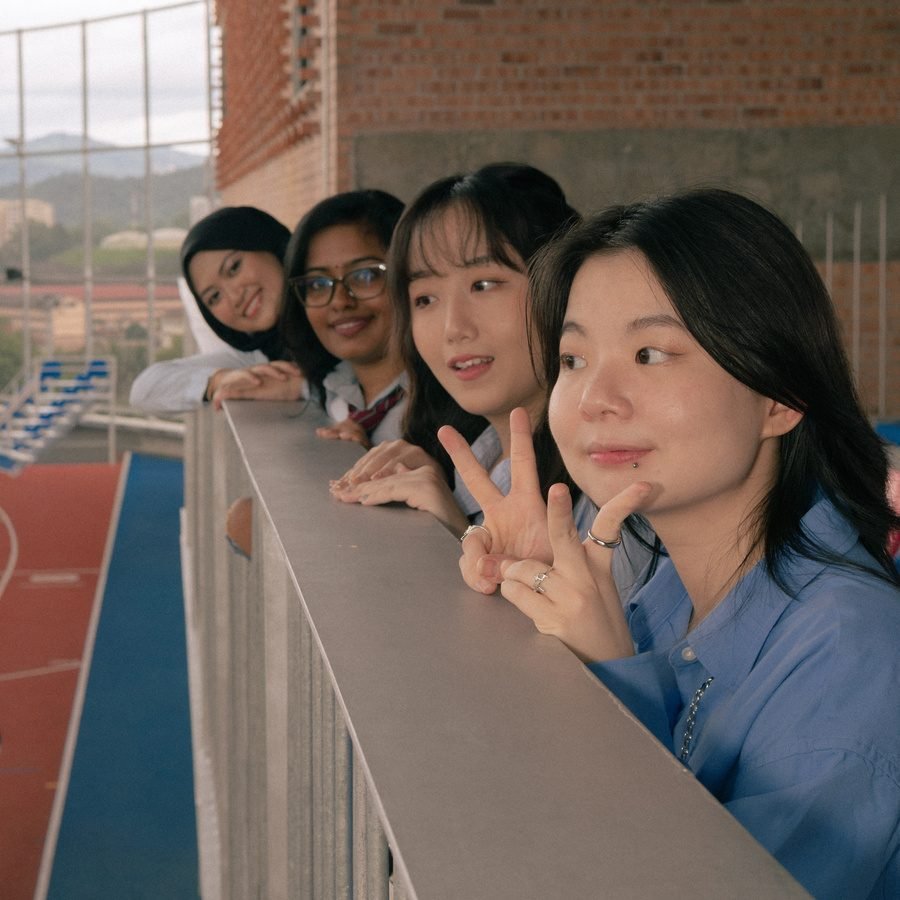 The same friends at the railing, one making a peace sign by her cheek.